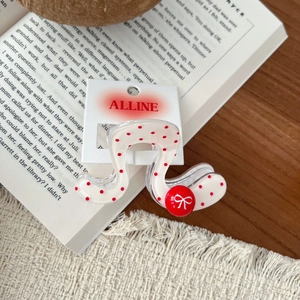 Close-up of wavy hair claw clip with red polka dots and bow detail on a vintage book