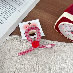 Red and white gingham hair claw clip with button detail on vintage wooden desk