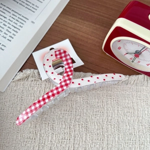 Close-up of a red and white checkered hair claw clip with a creative dot pattern