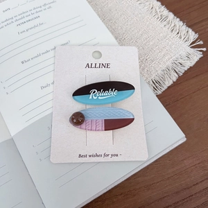 Detail of ALLINE hair clips with blue polka dots and beads on a decorative card