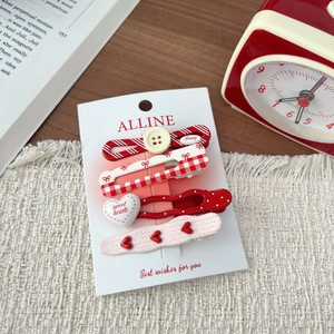 Detail of red sweet style hair clip set with hearts, bows and checkered patterns on a mat