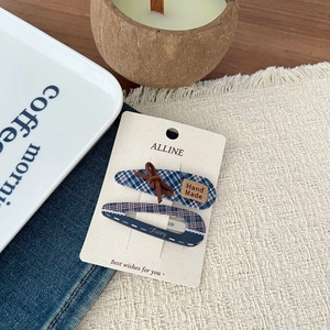 Detail of checkered hair clips with lace trim and bow on branded display card