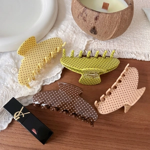 Detailed flat lay of polka dot hair claws in four colors on a rustic wooden background