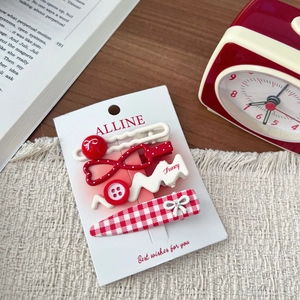 Set of four red and white Korean style hair clips with bow and heart motifs on a display card