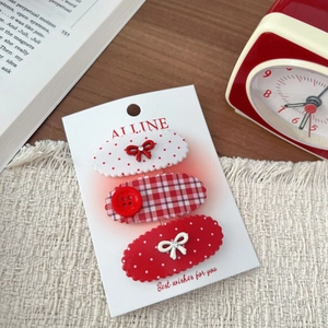 Set of 3 red and white polka dot hair clips with bows on a display card