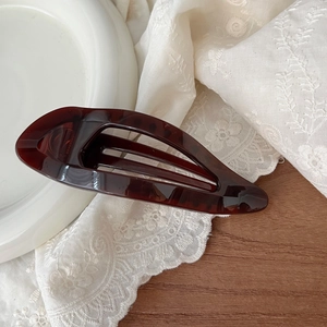 Close-up of elegant tortoise shell pattern hair claw on vintage lace and ceramic plate