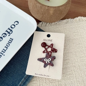 Close-up of star-shaped red polka dot and black-red checkered hair clips on card