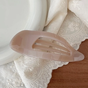 Detail view of hollow 11.5cm light brown hair claw clip on elegant lace backdrop