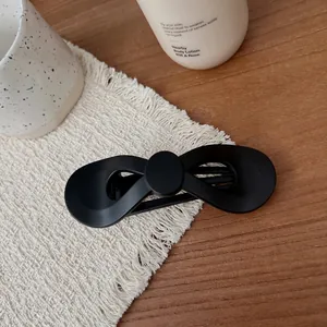 Nahaufnahme einer mattschwarzen Haarklammer mit Schleife auf einem gemütlichen Holztisch