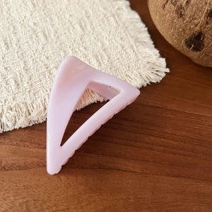 Minimalist light pink triangular matte resin hair claw clip for women on a wooden background