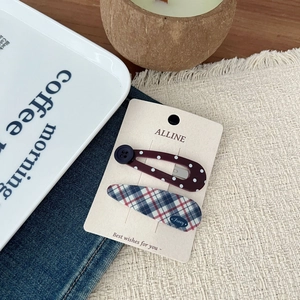 Detail shot of vintage plaid and polka dot hair clips set on rustic textile background