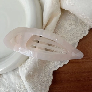 Detail of elegant 11.5cm hollow leaf hair claw clip in translucent pink acetate material