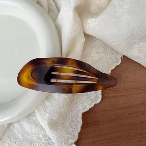 Macro detail of tortoiseshell pattern hair clip on elegant lace and ceramic display