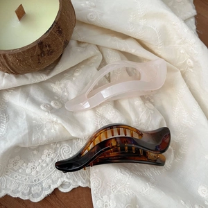 Detail of 11.5cm tortoiseshell and cream hair claws on embroidered white cloth
