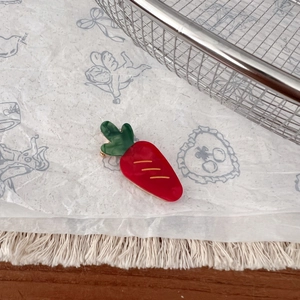 Détail d'une pince à cheveux créative en forme de carotte avec feuilles vertes et fini lisse