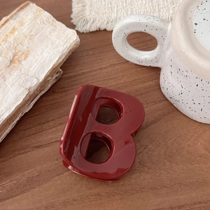 Gros plan d'une pince à cheveux rouge en forme de lettre B sur un décor de table