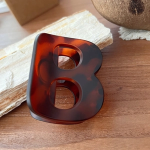 Détail de la pince à cheveux lettre B en motif écaille sur fond en bois naturel