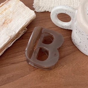Détail d'une pince à cheveux marron foncé en forme de B sur une table en bois