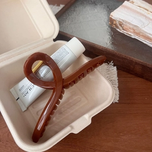 Detailed close-up of amber resin hair claw clip with golden spring in a gift box