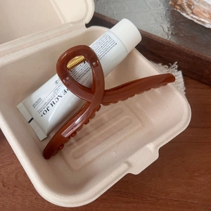 Detailed view of sunset orange glossy claw clip with elegant hollow pumpkin design