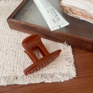 Detail of elegant hollow pumpkin-shaped hair claw clip in sunset orange on linen fabric