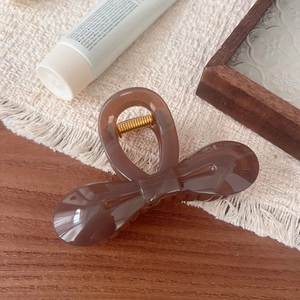 Detailed view of the brown resin butterfly hair claw clip on a warm cream textile background