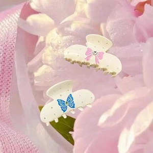 Detail of elegant wavy hair claws with pink bow and blue butterfly crystal accents