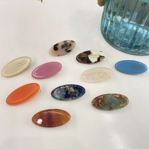 Flat lay of oval acetate hair clips in assorted tortoiseshell and solid colors