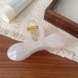 Macro shot of 10.5cm acetate ribbon bow hair claw clip with golden metal spring details