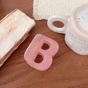 Détail de la pince à cheveux rose translucide en forme de B avec ressort métallique