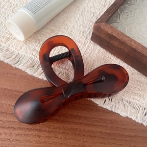 Detail of dark brown tortoiseshell bow hair claw clip with elegant resin texture