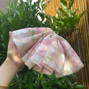 Detailed close-up of pink floral fabric hair scrunchie with pleated texture and soft layers