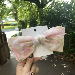 Close-up of pink floral fabric bow hair clip with decorative mesh butterflies