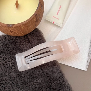 Detail of a light pink rectangular hair claw clip with a marble acrylic resin texture