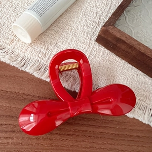 Macro view of a 10.5cm red bow hair claw clip with glossy resin and gold spring details