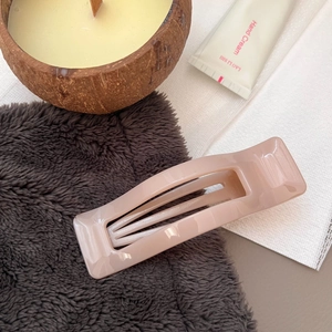 Detail view of a pale nude pink rectangular hair claw clip on soft textured fabric