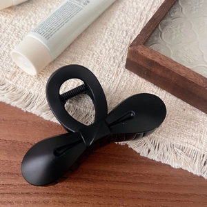 Detailed macro view of matte black bow hair claw clip with elegant frosted texture finish