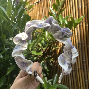 Detail of ruffled floral headband with purple flowers and white scalloped lace edges