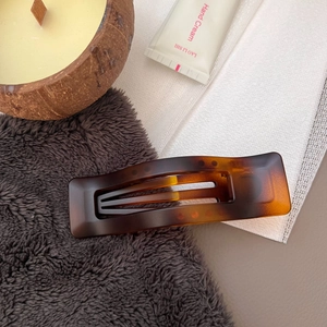 Detailed view of brown tortoiseshell hair claw clip with cutout design on fabric