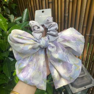 Detail view of a large purple floral bow hair scrunchie with Korean style patterns