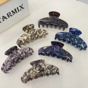 Detailed close-up of six assorted marble patterns on acetate hair claw shark clips