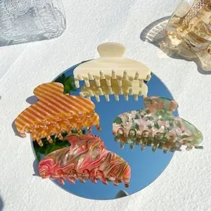 Detailed macro view of four marble texture acetate hair claws on a mirror surface