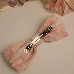 Detail of pink tulip floral print bow hair clip with polished metal automatic clip mechanism