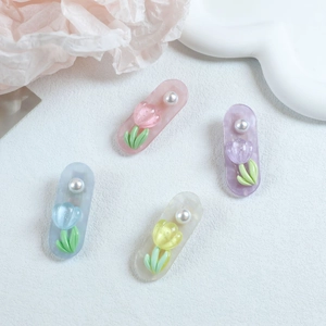 Detail of four tulip resin hair clips with pearls in pink, purple, blue, and yellow colors