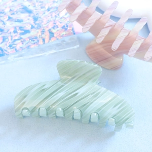 Détail de la texture marbrée vert clair et de la finition lisse de la pince à cheveux en acétate