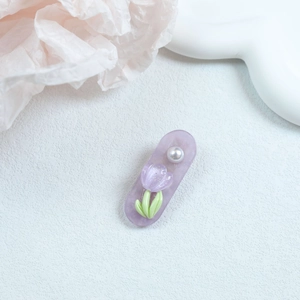 Detailed view of a purple tulip hair clip with floral accents and a white pearl embellishment