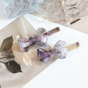 Détail de barrettes nœud en acétate violet avec gravure France Handmade et texture marbre