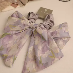 Detail of lavender floral bow scrunchie featuring organza fabric and satin finish