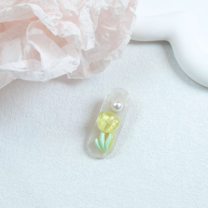Detail of cream hair clip with elegant pearl and a yellow tulip floral charm