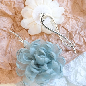 Detail von cremeweißen und morandiblauen Organza-Blumen-Haarspangen auf Silbermetall